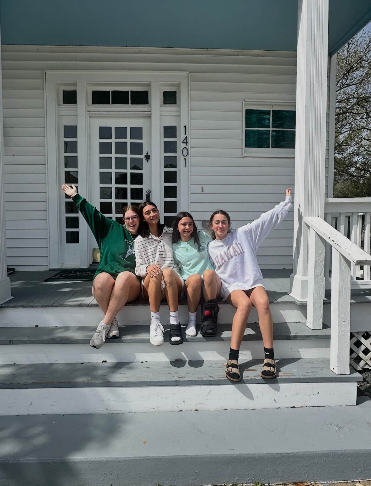 Family sitting on the front porch steps at White Magnolia Galveston
