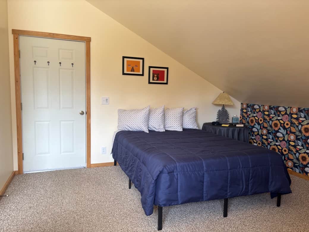 Queen bed and entry door to stairway. 