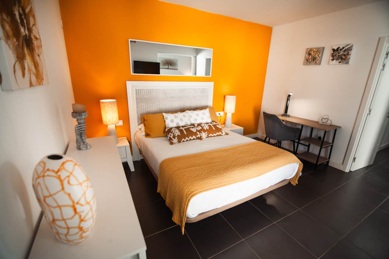 Dormitorio principal con cama de matrimonio, cabecero blanco, colcha amarilla y aire acondicionado