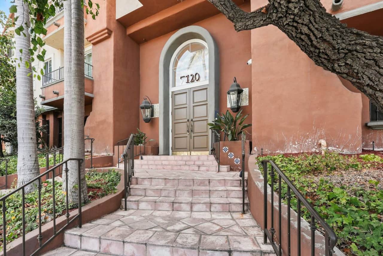 Charming Spanish-style entrance with an arched wooden door and iron gate.