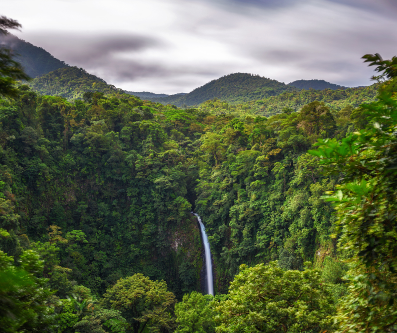 Landscape overlooking a lush valley and distant hill range near Villa Sueño Costa Rica, with a small cascading waterfall