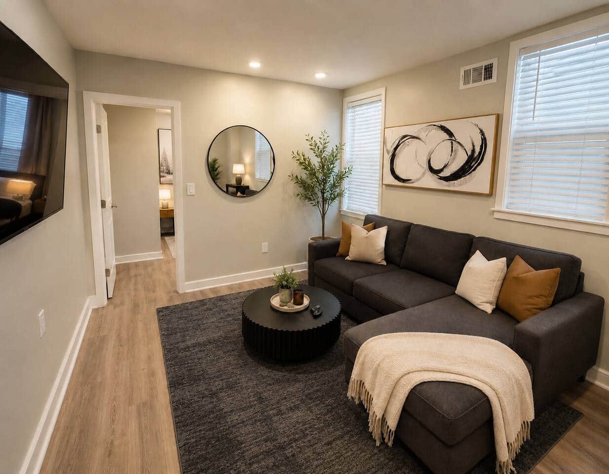 Modern and cozy living room with a dark gray sectional sofa, large Roku smart TV, stylish dining nook, and warm modern decor. Features comfortable seating, natural lighting, and a relaxing contemporary vibe perfect for entertaining or unwinding.