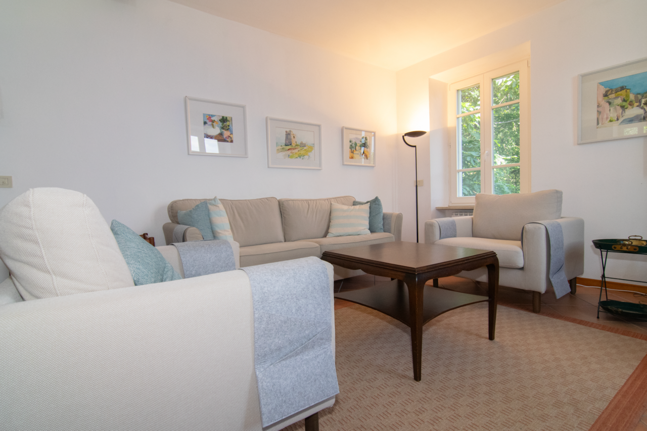 Bright living room with sofa, TV, fireplace, and Wi-Fi in the villa overlooking Lake Garda and nature.