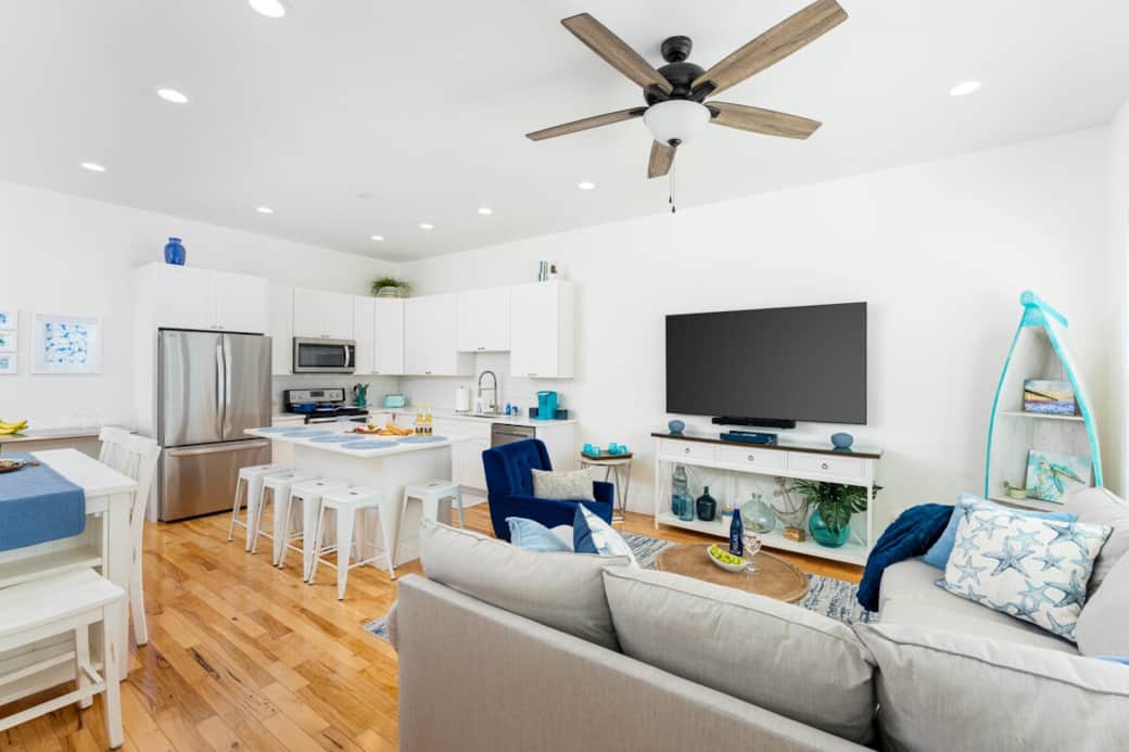Open-concept living area with 10-foot ceilings, coastal décor, and natural light—perfect for gathering, movie nights, and family time.