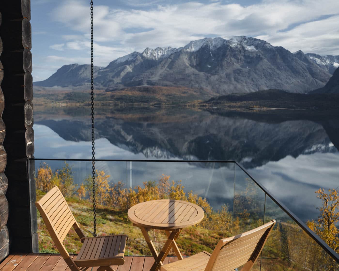 Terrasse mit Stühlen über dem spiegelglatten Fjord