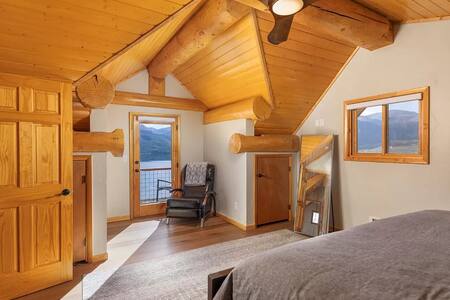 Loft bedroom with exposed beams and lake view windows