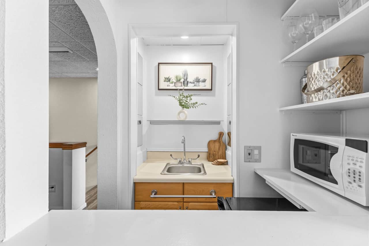 Cozy kitchenette stocked with everything you need — sink, microwave, glassware, and bar accessories.