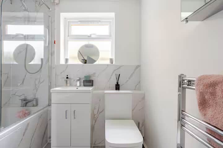 Bright modern bathroom with marble-effect tiles, bath, and complimentary starter toiletries.
