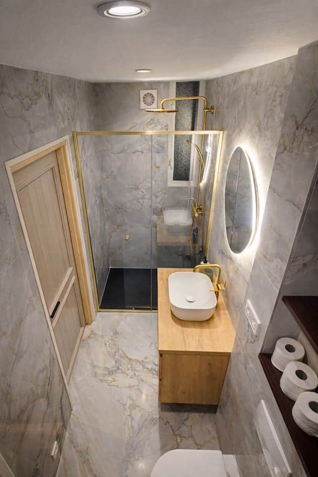 Luxe badkamer met regendouche, marmerlook en warme houten details voor een echt hotelgevoel.