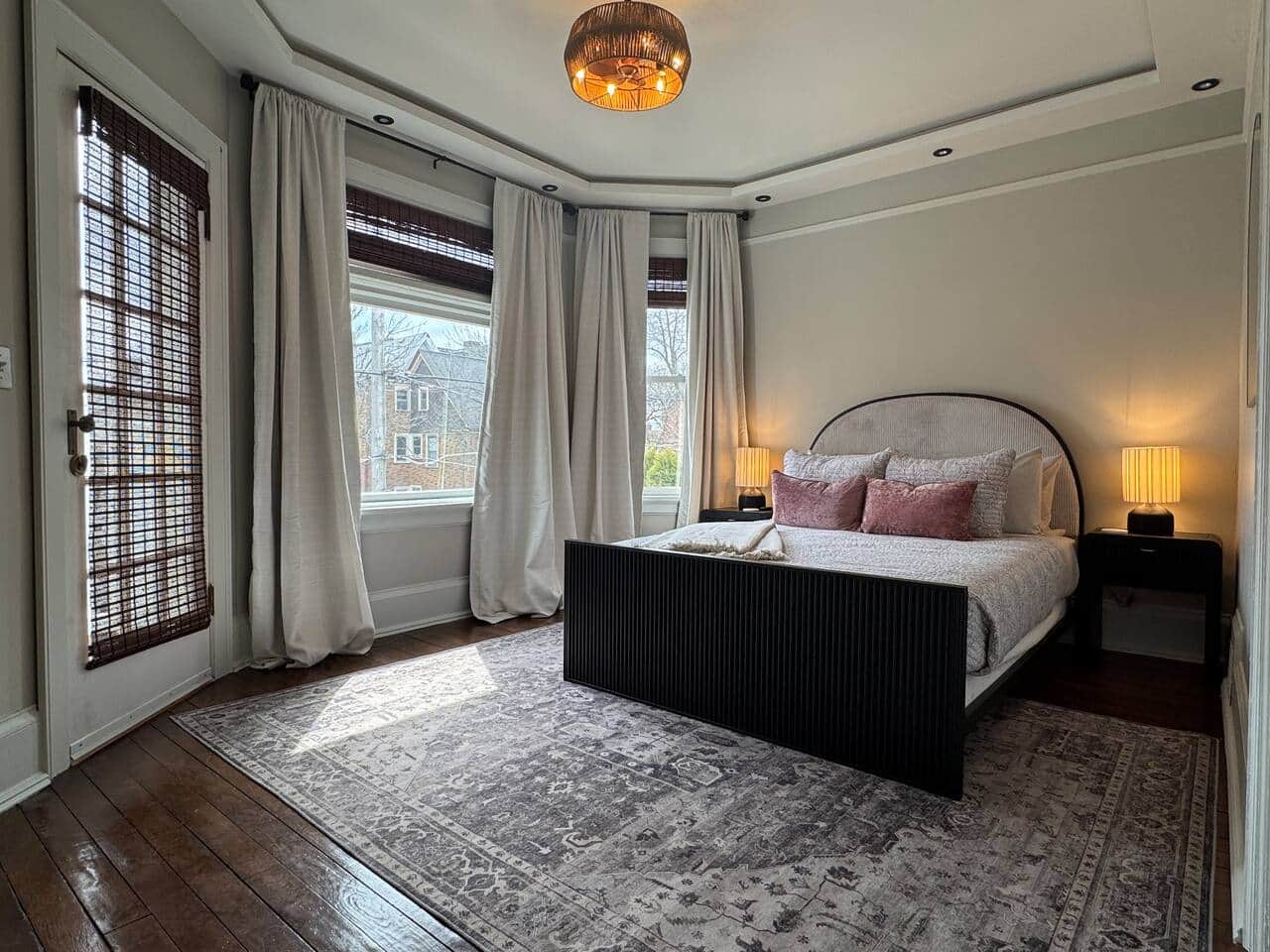 Elegant and sun-filled bedroom with large bay windows and soft, flowing curtains.