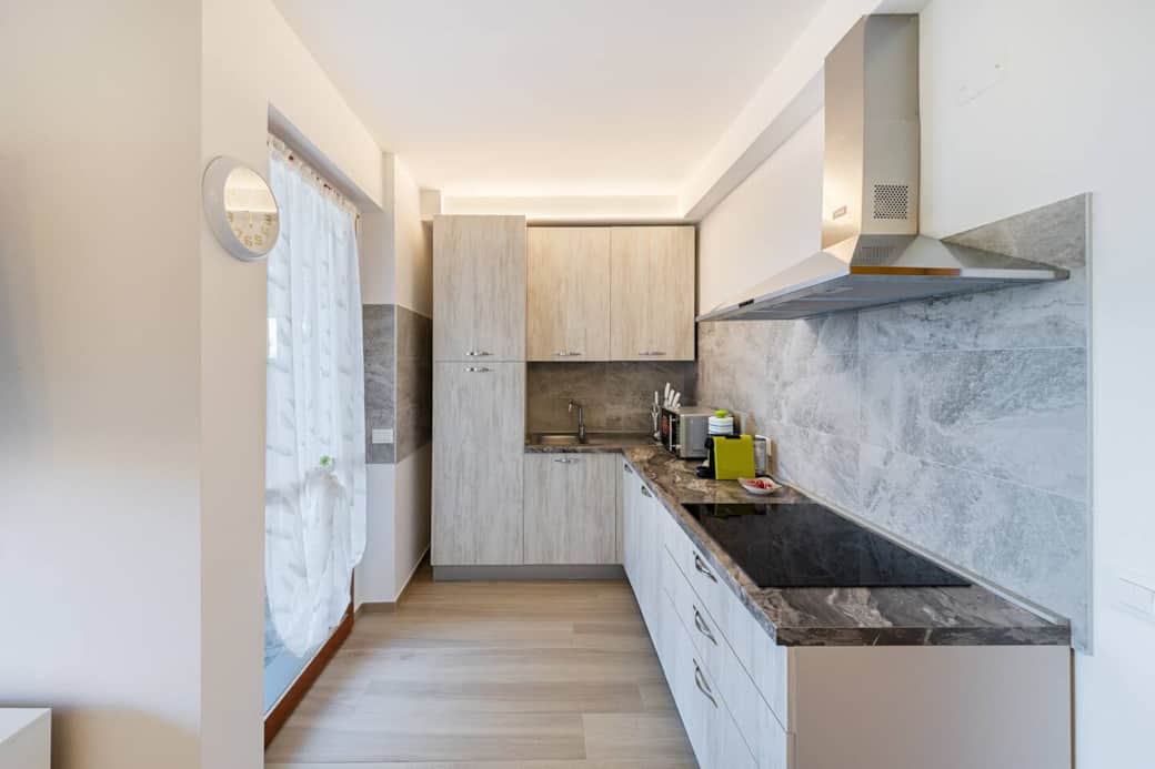 Cucina completamente attrezzata di utensili vari, piatti, microonde, macchinetta del caffè, forno, frigo, freezer, lavastoviglie, cappa aspirante e piano a induzione.