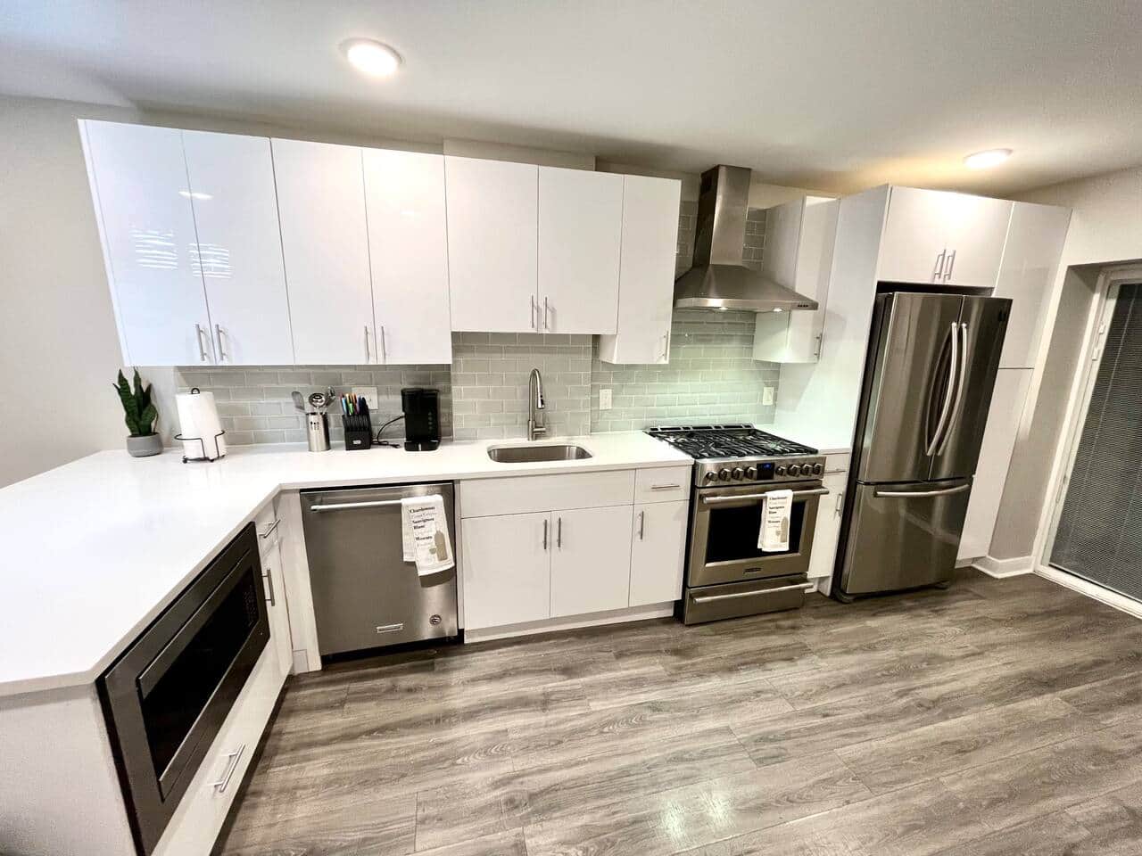 Spacious and well-equipped kitchen featuring an expansive quartz island, a top-of-the-line 36-inch refrigerator, a high-performance oven hood, a microwave for efficient cooking, a dishwasher, and a coffee maker for that perfect cup of joe.