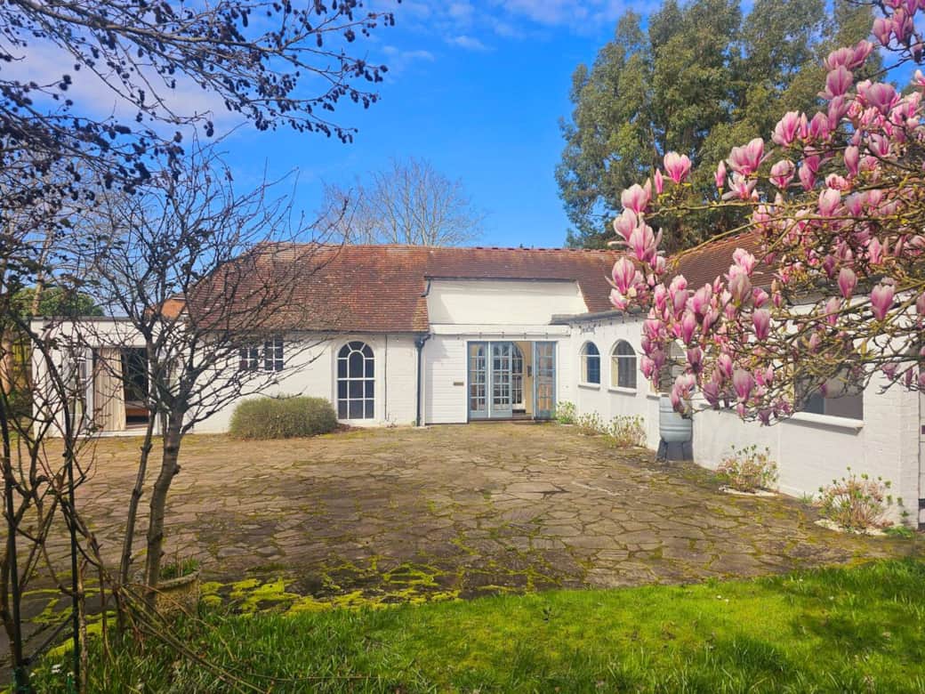Showing off the beautiful farmhouse cottage front with meditarranean style arches and a huge courtyard for parking.