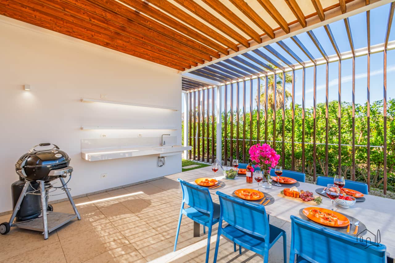 Covered patio dining space with a modern pergola and lush greenery views.
