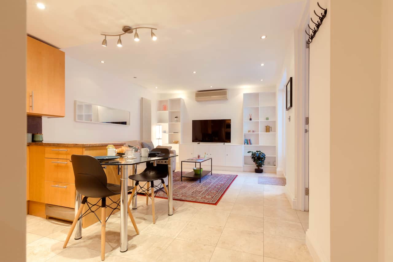 Open-plan dining and living space with glass table and built-in shelving