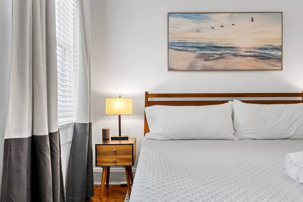 Close up of the king mid century modern wood bed frame, bedside table, lamp with power outlets, and sound machine!