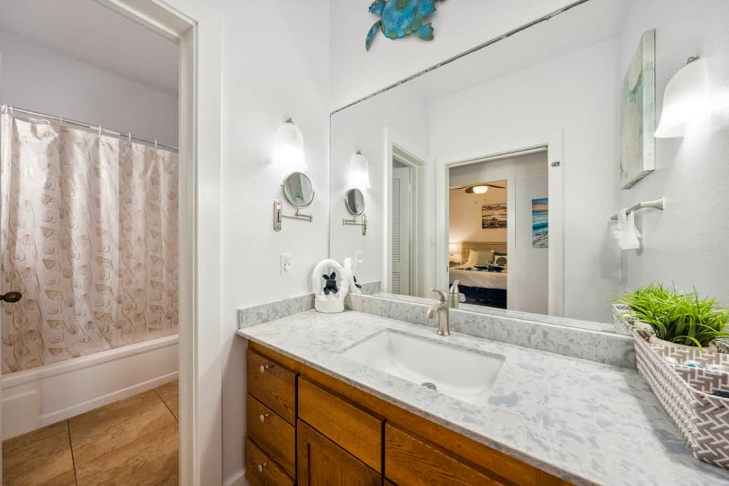 Bright and coastal bathroom with a spacious vanity, seashell-themed shower curtain.