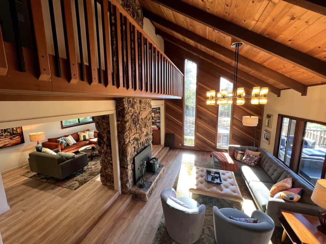 Living Room with double vaulted ceilings, redwood accent wall surround, and propane fire place. There are two shallow steps (pictured) from the TV Room/Den to the Living Room.