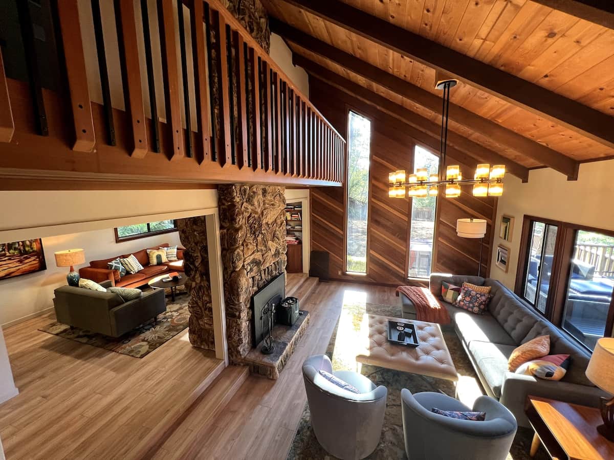 Living Room with double vaulted ceilings, redwood accent wall surround, and propane fire place. There are two shallow steps (pictured) from the TV Room/Den to the Living Room.