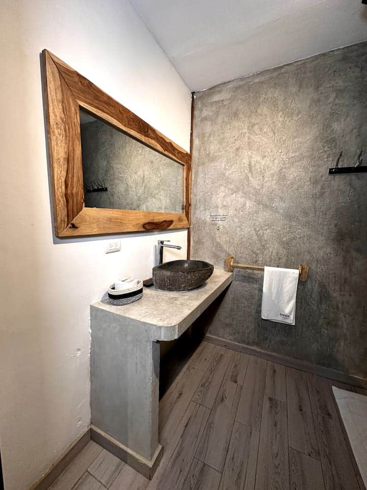 Natural stone basin on a concrete vanity under a wood-framed mirror, Saboga Lodge, Panama
