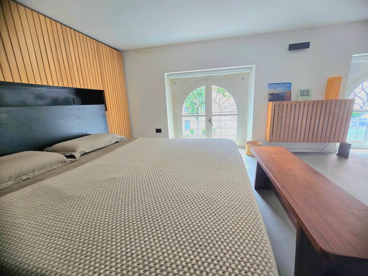 Bright sleeping area with arched window and timber detailing