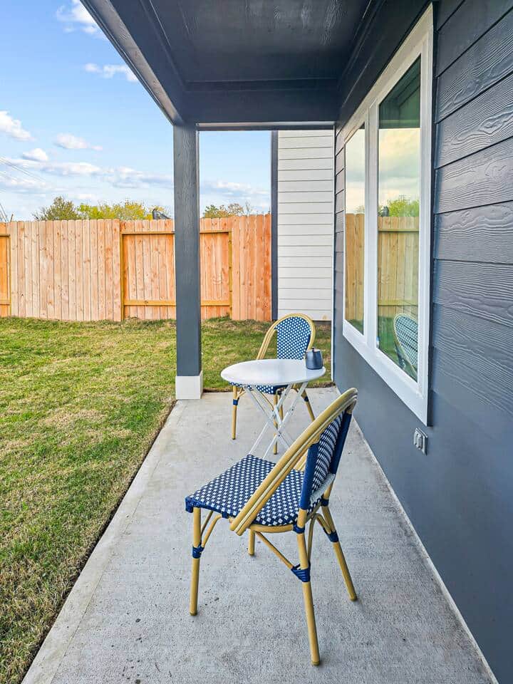 Cozy covered patio with outdoor seating, perfect for morning coffee or relaxing evenings in the fenced backyard.