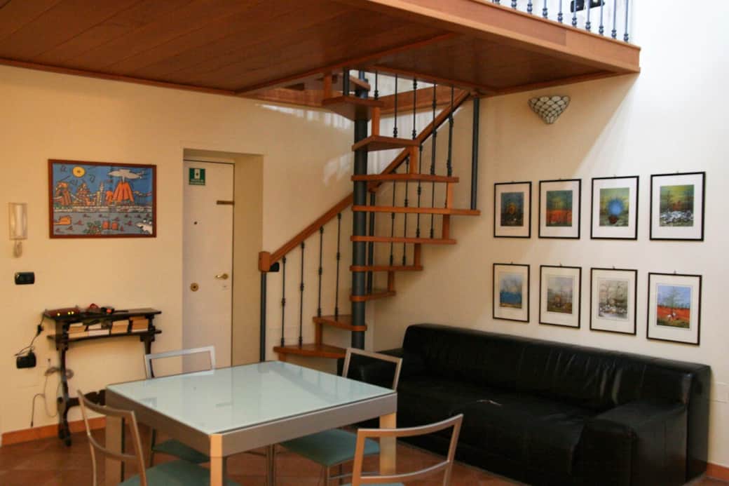 View of the living room, with sofa, table (4 to 6 seats) and stairs to the mezzanine