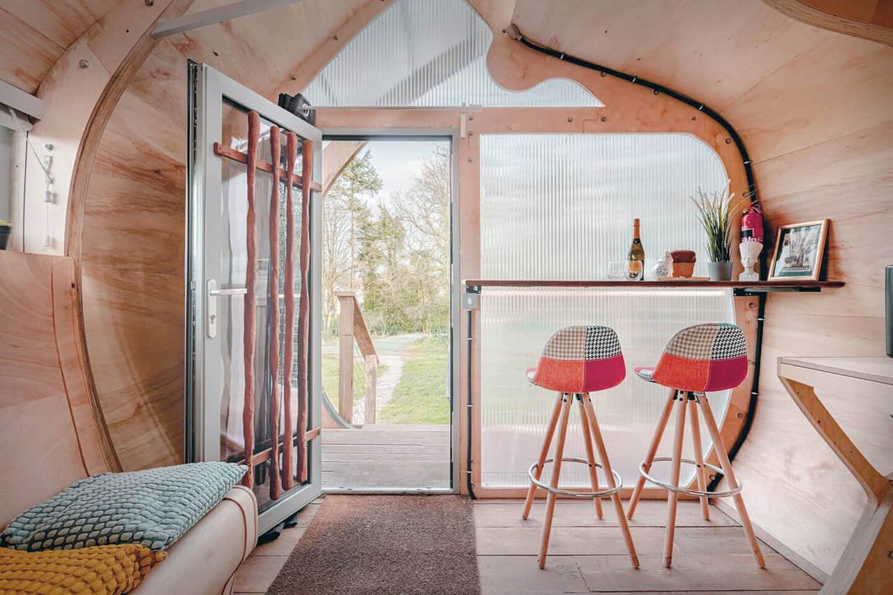 Monocoque Cabin — The breakfast bar with two stools, and the door open to the canal-side garden beyond the cabin.