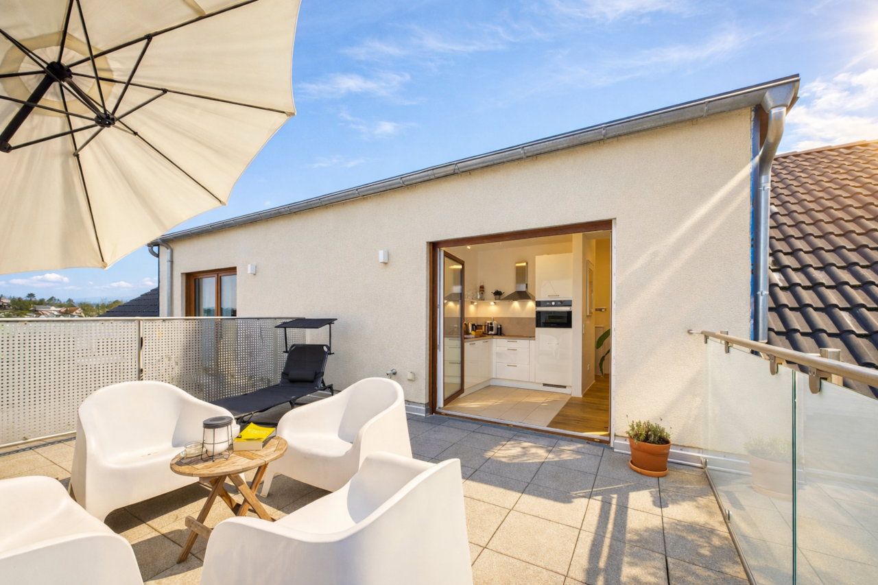 Großzügige, sonnige Dachterrasse mit bequemen Loungemöbeln und Sonnenschirm