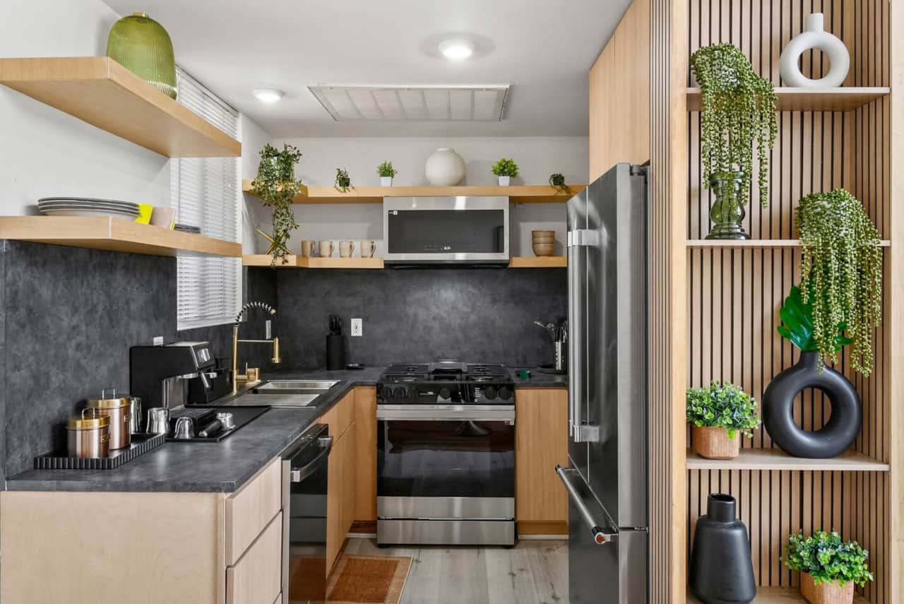 Built-in fridge sits beside decorative shelving with greenery accents.