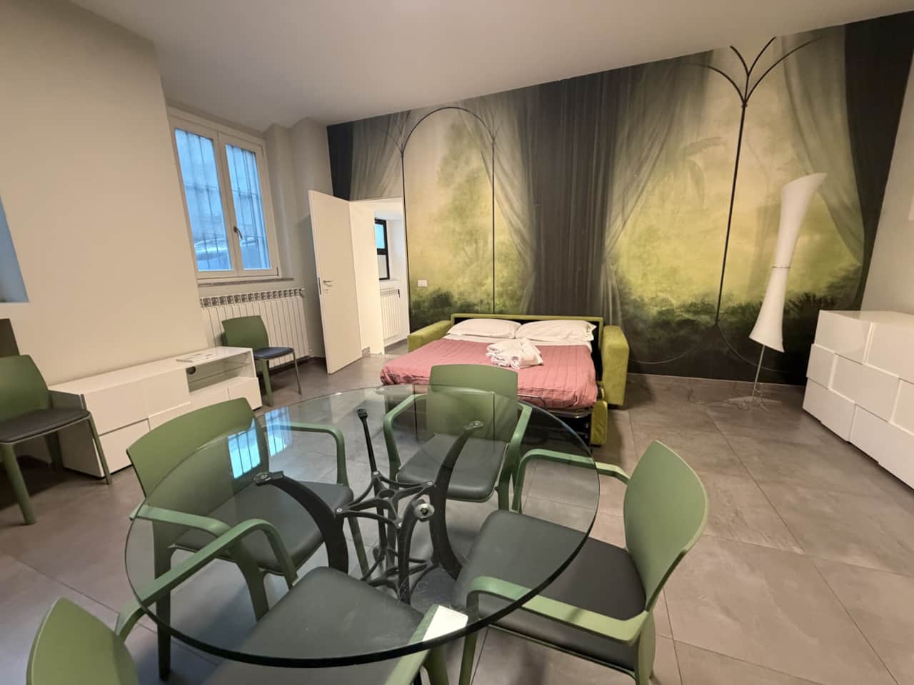 Mesa de comedor con sillas y sofá rosa en el espacio diáfano