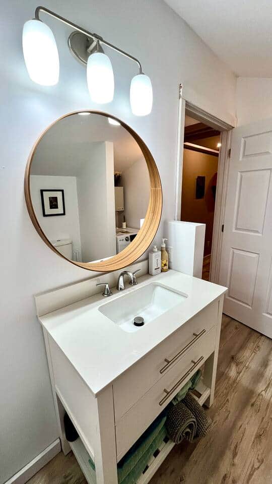 Sleek bath vanity with round mirror, bright lighting, and fresh towels. Sleek bath vanity with round mirror, bright lighting, and fresh towels.