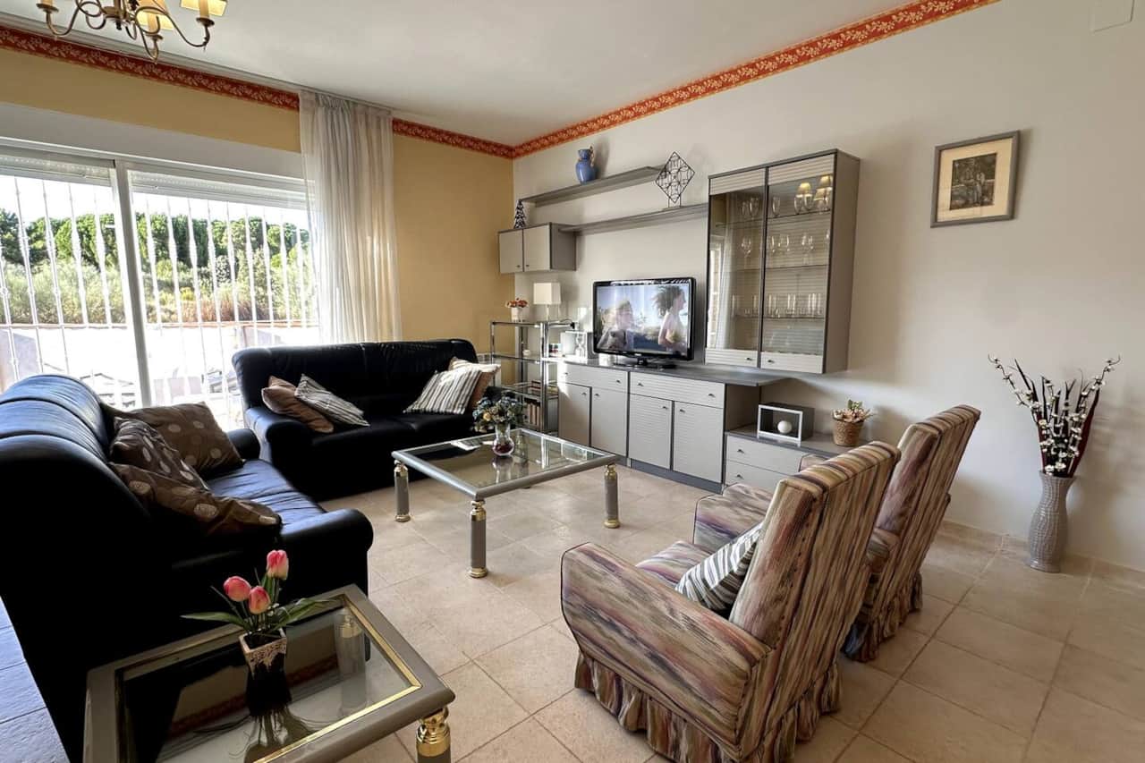 Salón amplio con dos sofás, TV y vistas al jardín