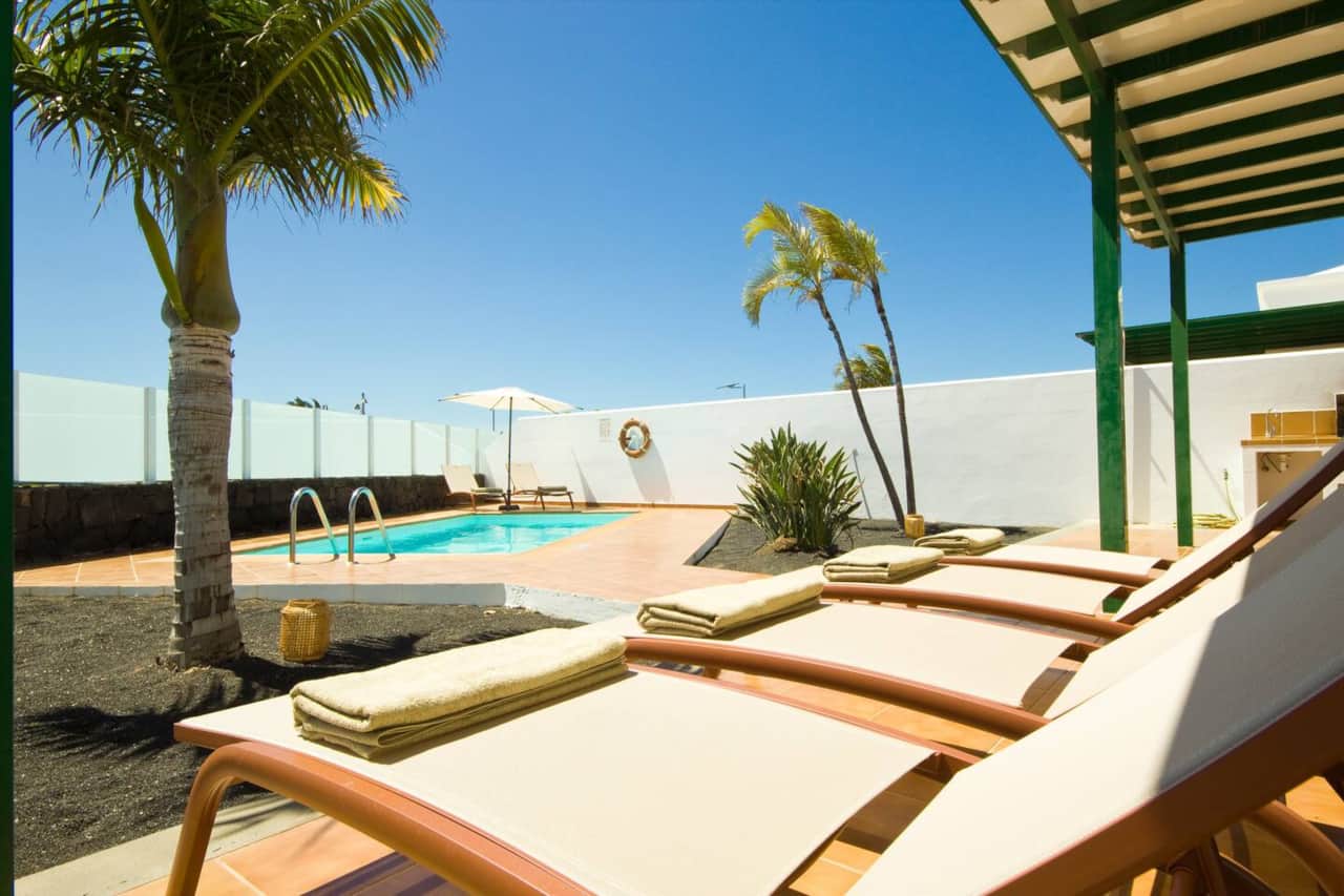 Private swimming pool surrounded by sun loungers at an AZ Rentals holiday villa