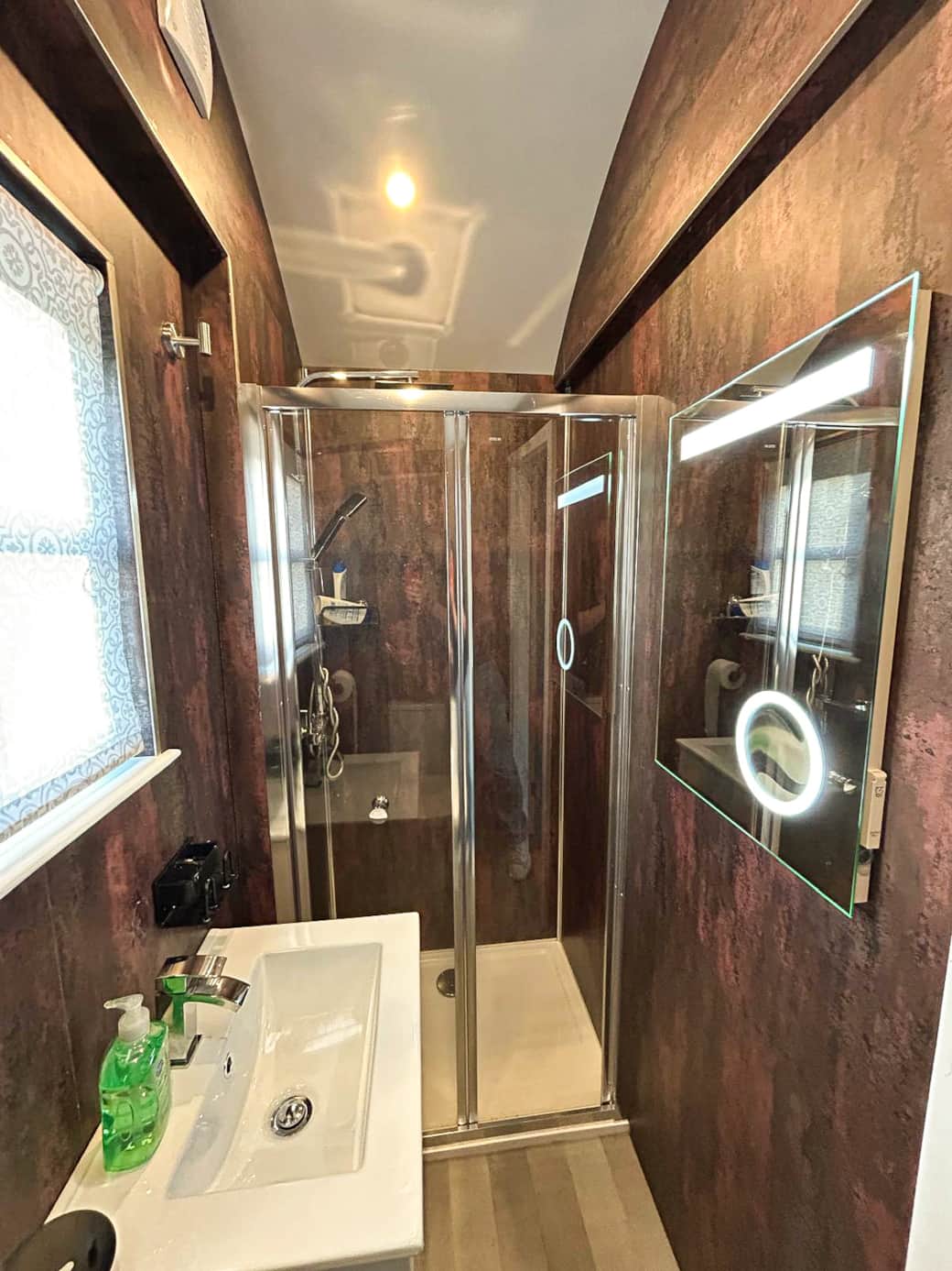 Modern ensuite with walk-in shower and warm feature wall finishes.