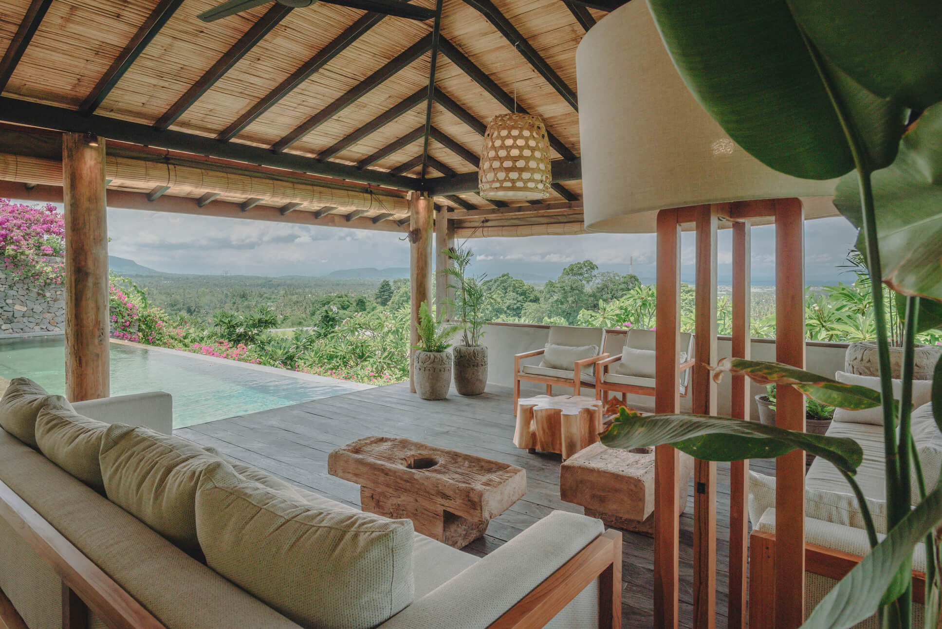 Open-air living area and infinity pool at Villa Verde, Sumberkima, Bali showing wooden furniture and valley/volcano views