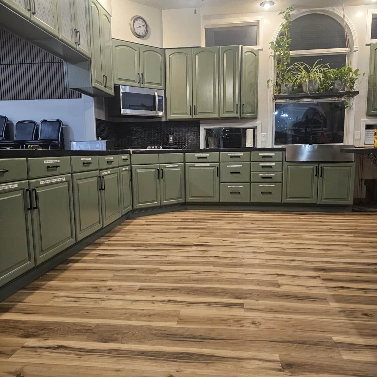 Kitchen with green cabinets, dark countertops, and hardwood floors