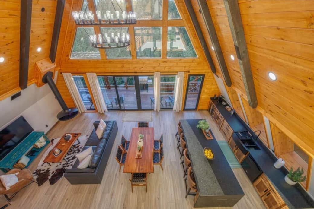 The large windows will bring you closer to nature. A large luxury hanging trumpet-shaped fireplace, a spacious open floor plan, and a large black iron chandelier really set the mood for a perfect space for you to relax or entertain.