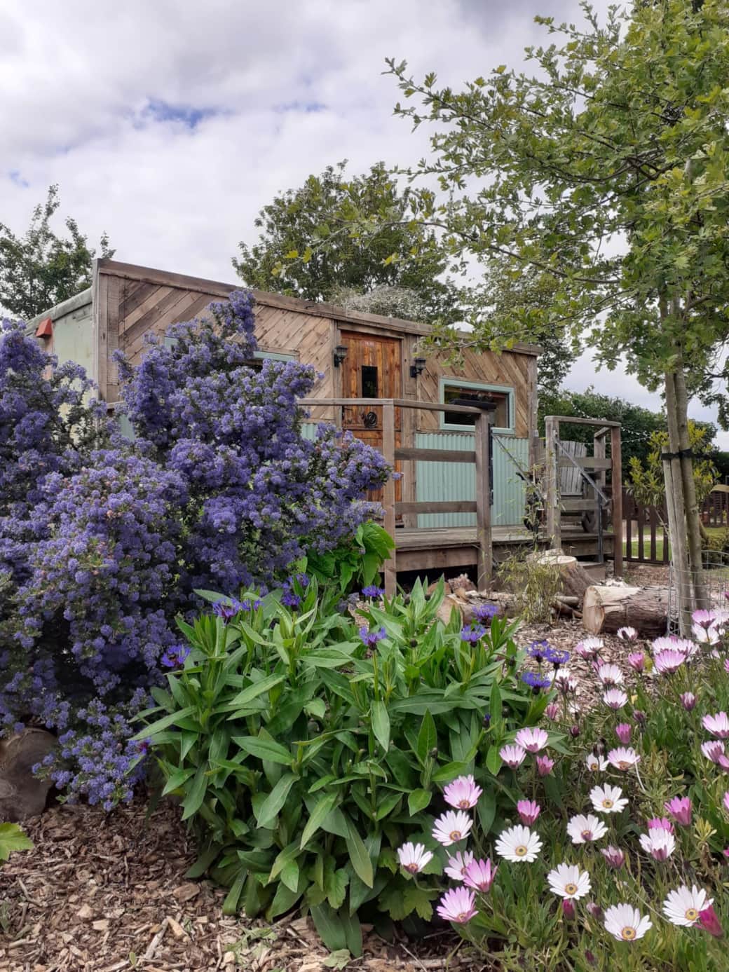 The Den Hut glamping pod sleeps 2 and has a rustic exterior with wrinkly tin and pallet wood fascia.