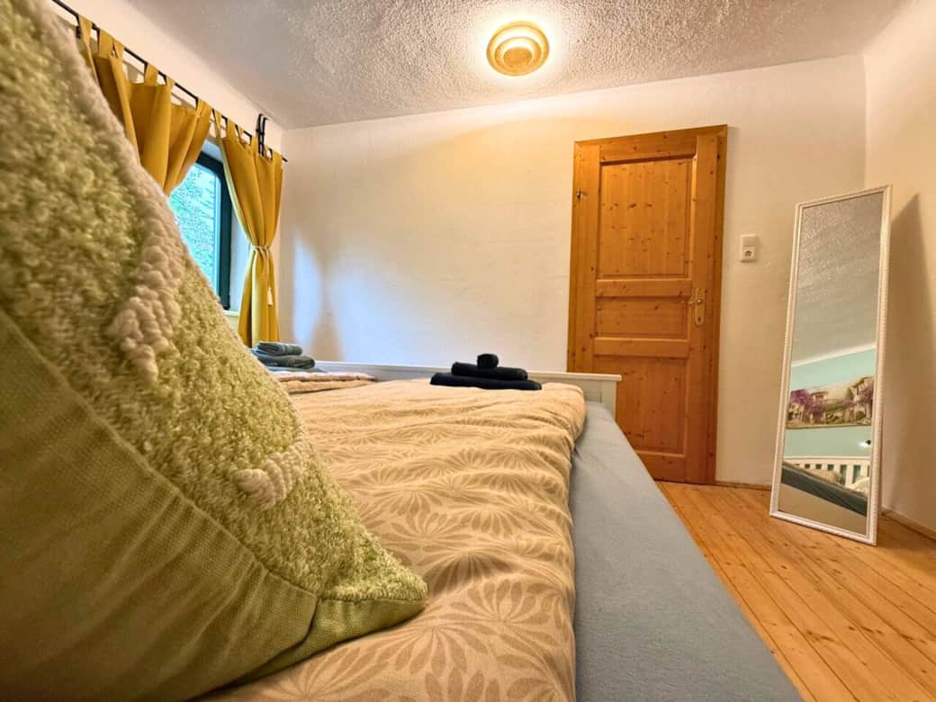 Schlafzimmer mit Doppelbett, Kleiderschrank und Spiegel. Fenster mit AUsblick auf den Fluss