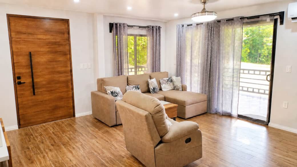 Relax in the open-concept living room featuring comfortable seating, Smart TV, AC, and easy access to the covered veranda. The sofa converts into a queen sleeper, allowing the home to accommodate up to 9 guests.