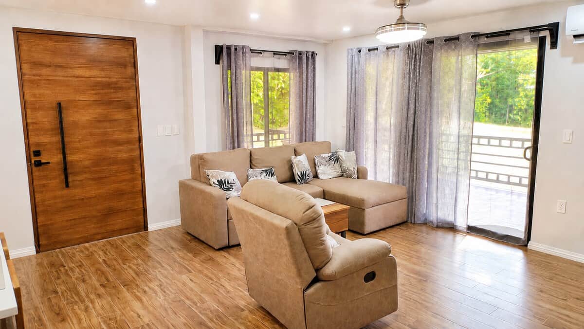 Relax in the open-concept living room featuring comfortable seating, Smart TV, AC, and easy access to the covered veranda. The sofa converts into a queen sleeper, allowing the home to accommodate up to 9 guests.