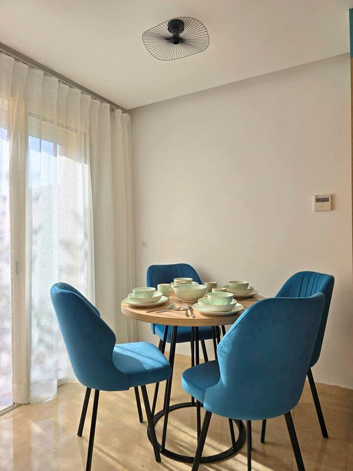 Salle à manger cosy et lumineuse, idéale pour partager vos repas en famille ou entre amis. La table ronde, est entourée de chaises en velours confortables pour des moments conviviaux dans un cadre chaleureux.