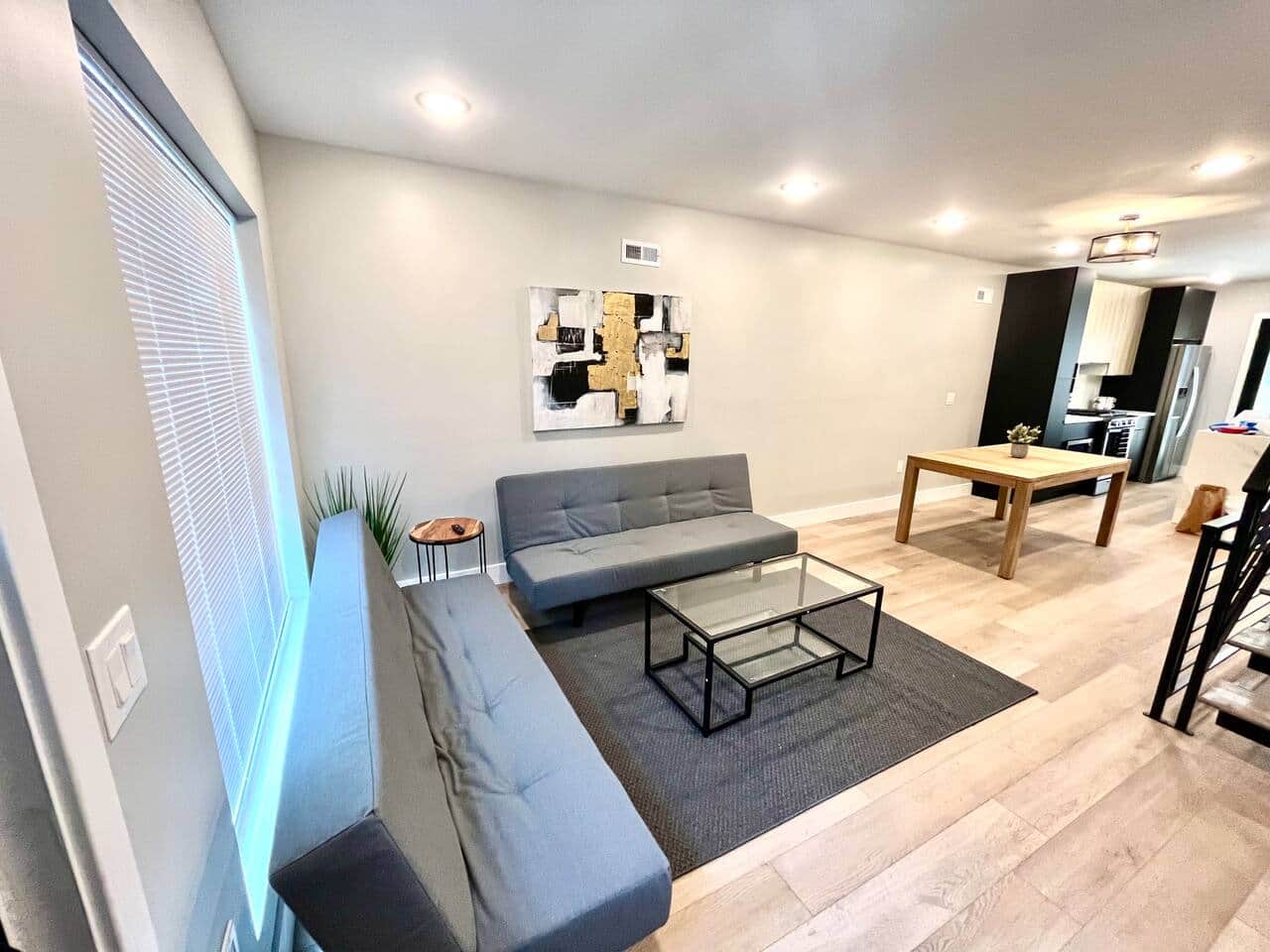 The living room, highlighted by large windows, is designed for relaxation and features a flat-screen TV along with two comfortable futon sofa beds to accommodate additional guests.