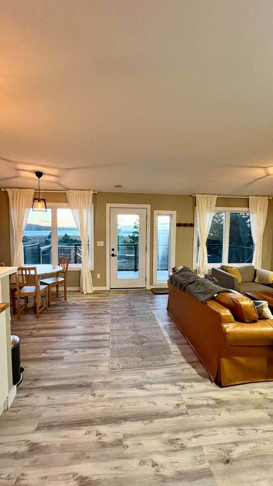 Sunny open-plan lounge with deck access and sweeping water views Sunny open-plan lounge with deck access and sweeping water views