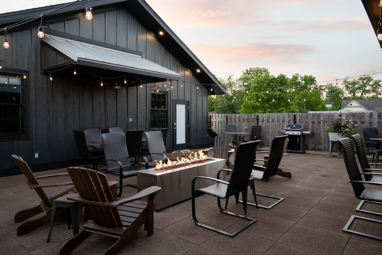 The Barn Burner's rooftop patio at dusk with a lit fire table, string lights, and seating.