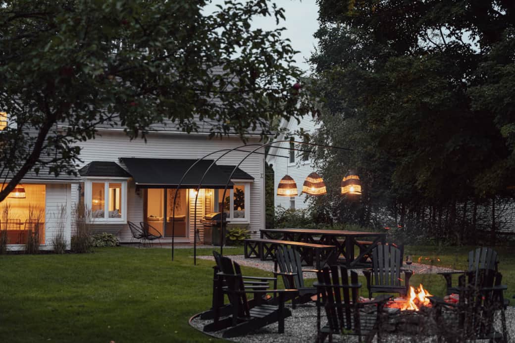 The beautiful backyard features a fire pit, Adirondack chairs & a large outdoor table.