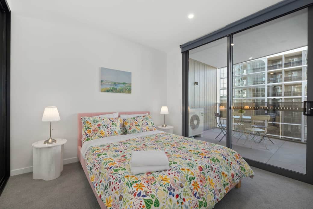 “The bedroom has a queen-size bed, two bedside tables with a lamp, and a spacious balcony just outside the room.