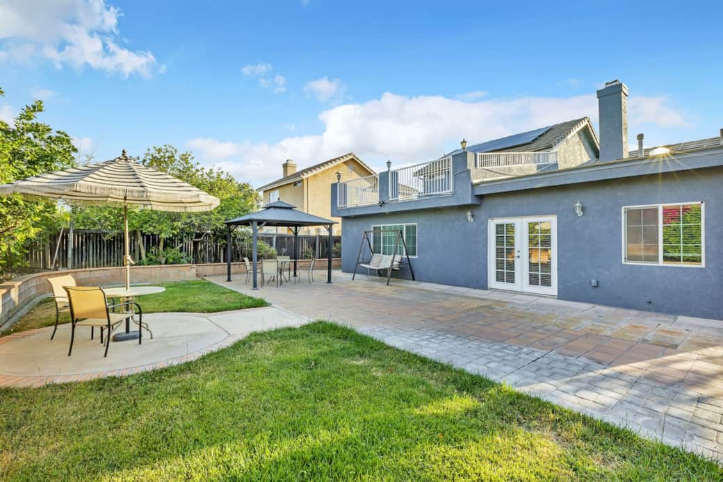 Backyard with patio, gazebo, dining, swing, and lawn for relaxing or entertaining.