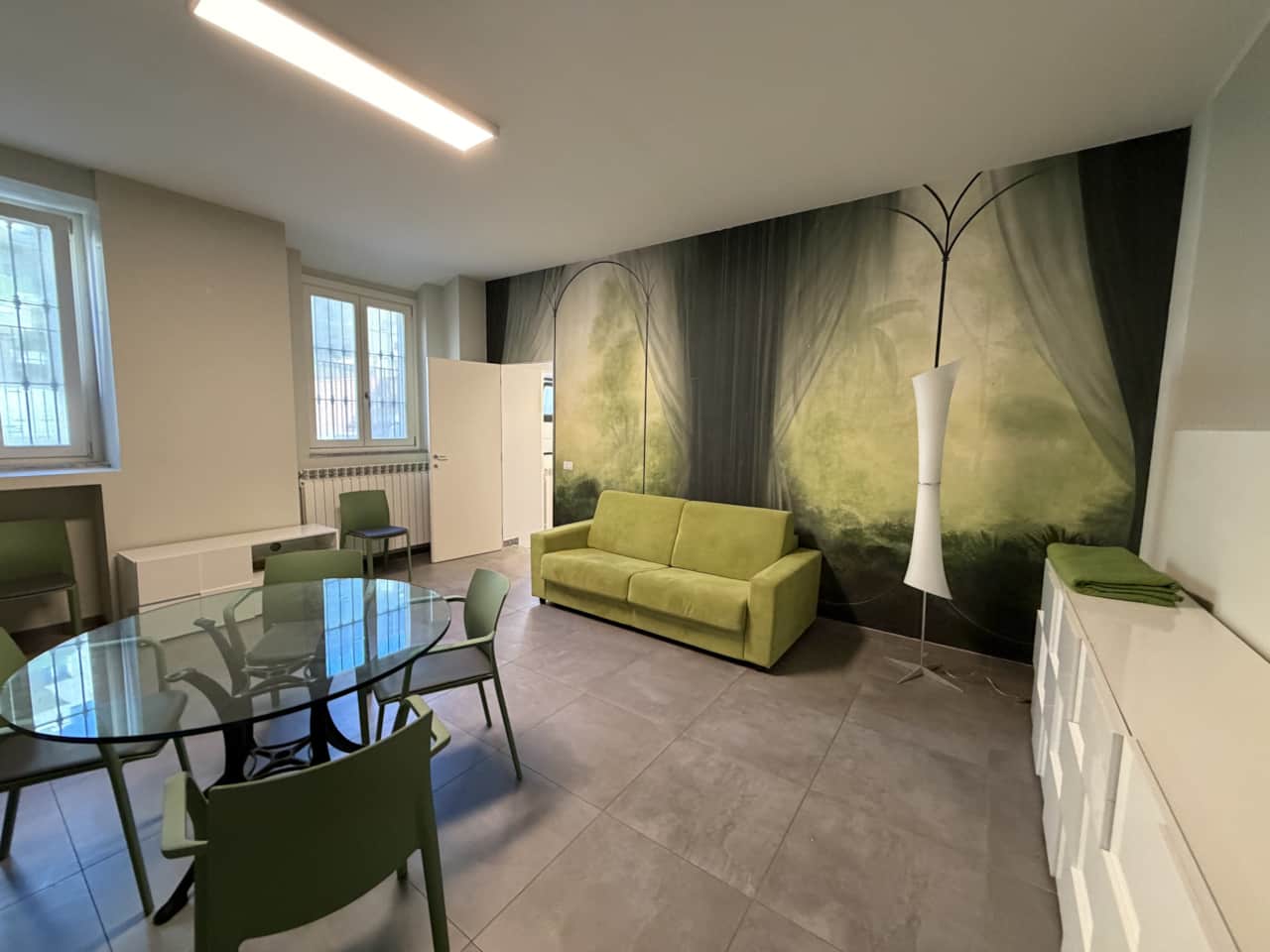 Salón con sofá verde y mesa redonda, en el centro de Monza